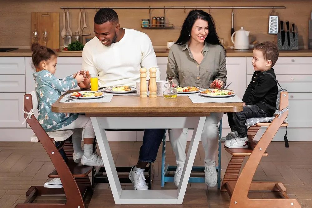 A family eating together; the children sit at table height in Fornel chairs in walnut and dark walnut finishes